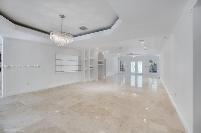 unfurnished living room featuring an inviting chandelier, a tray ceiling, built in features, french doors, and crown molding