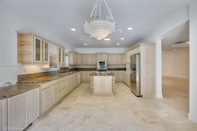 kitchen with pendant lighting, appliances with stainless steel finishes, a kitchen island, dark stone countertops, and sink