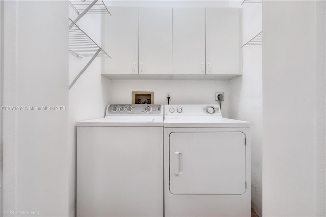 clothes washing area featuring independent washer and dryer and cabinets