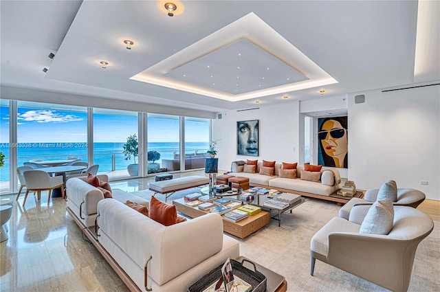 living room with a water view and a tray ceiling