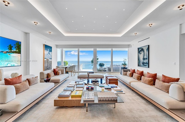 living room featuring a raised ceiling and a water view