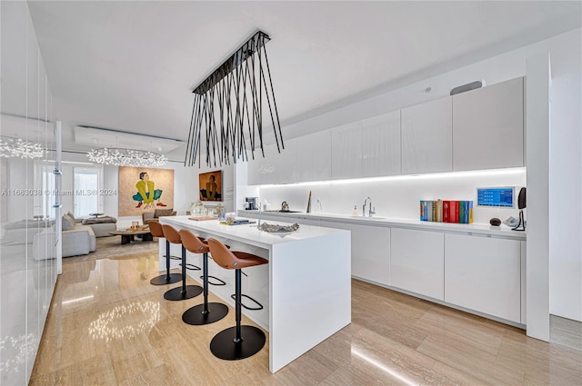 kitchen with white cabinets, hanging light fixtures, a kitchen island, and a breakfast bar area