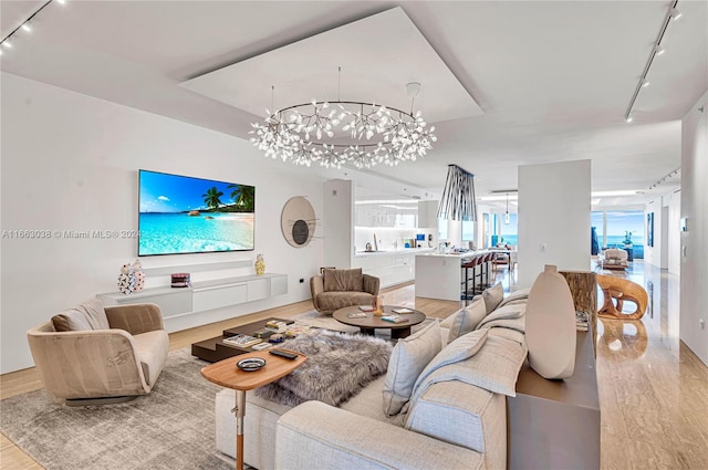 living room with a chandelier, light hardwood / wood-style floors, and rail lighting