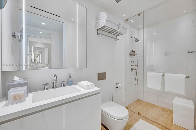 bathroom with a tile shower, tile patterned flooring, vanity, and toilet