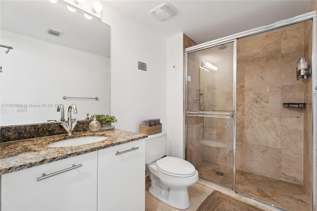 bathroom featuring vanity, a shower with shower door, and toilet