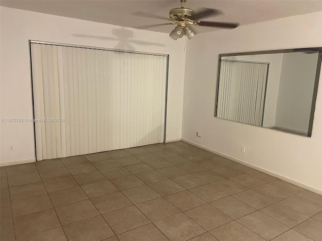 unfurnished bedroom featuring a closet, tile patterned flooring, and ceiling fan