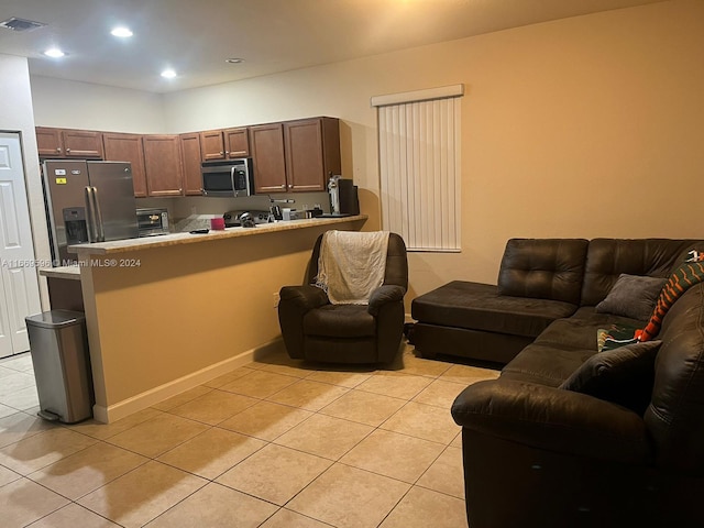 kitchen featuring kitchen peninsula, a breakfast bar area, light tile patterned floors, and stainless steel appliances