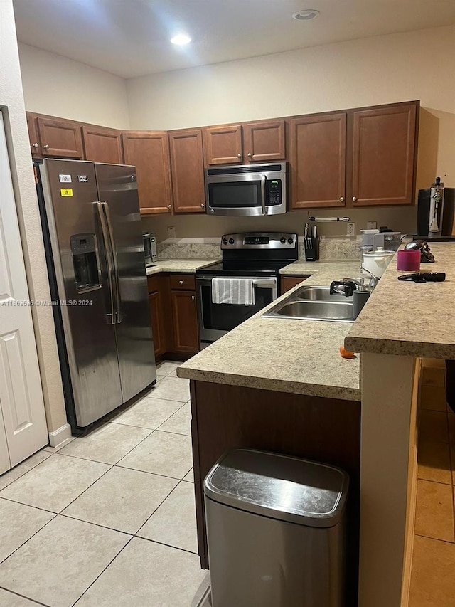 kitchen with a kitchen breakfast bar, light tile patterned flooring, sink, and stainless steel appliances