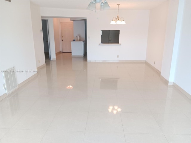 tiled empty room with a notable chandelier