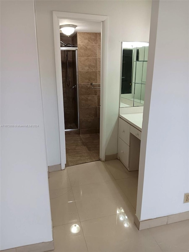 bathroom featuring a tile shower, tile patterned floors, and vanity