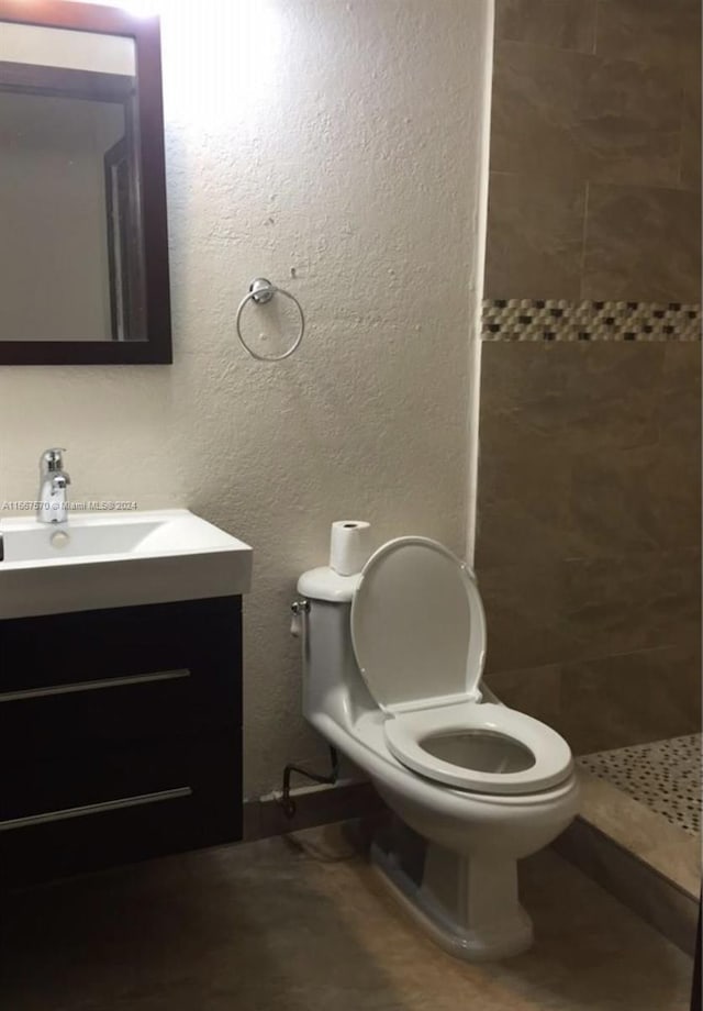 bathroom featuring tiled shower, vanity, and toilet