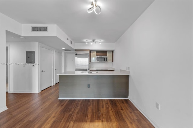 kitchen featuring stainless steel appliances, a peninsula, visible vents, light countertops, and dark wood finished floors