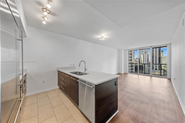 kitchen featuring appliances with stainless steel finishes, light countertops, dark brown cabinets, floor to ceiling windows, and a sink