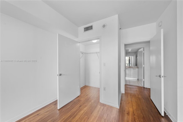 unfurnished bedroom featuring baseboards, a closet, visible vents, and wood finished floors