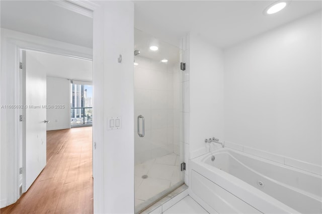 full bathroom featuring recessed lighting, a shower stall, a bath, and wood finished floors