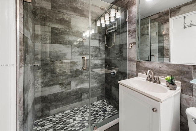 bathroom with vanity, toilet, tile walls, and a shower with door