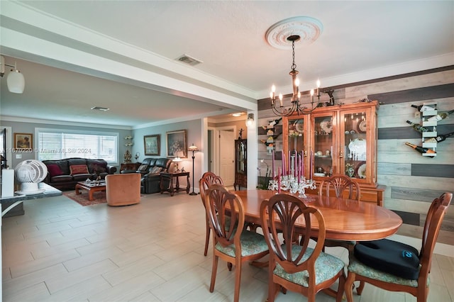 dining area featuring ornamental molding, a notable chandelier, and wooden walls