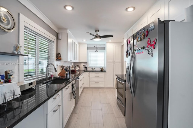 kitchen featuring ceiling fan, sink, white cabinetry, appliances with stainless steel finishes, and dark stone counters