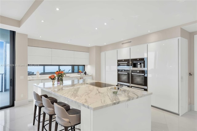 kitchen with modern cabinets, white cabinets, a kitchen bar, black electric cooktop, and recessed lighting