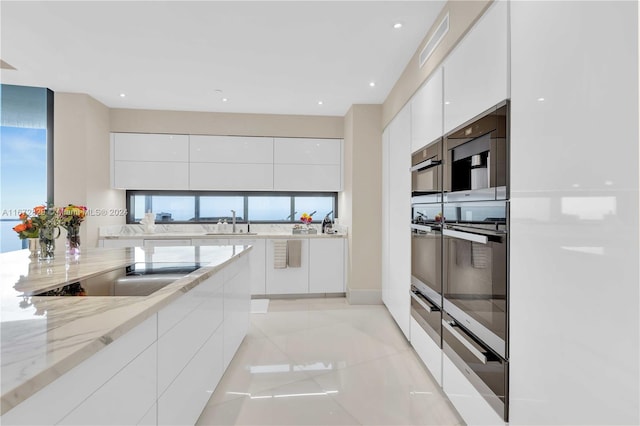 kitchen with modern cabinets, white cabinetry, light tile patterned floors, light stone countertops, and recessed lighting