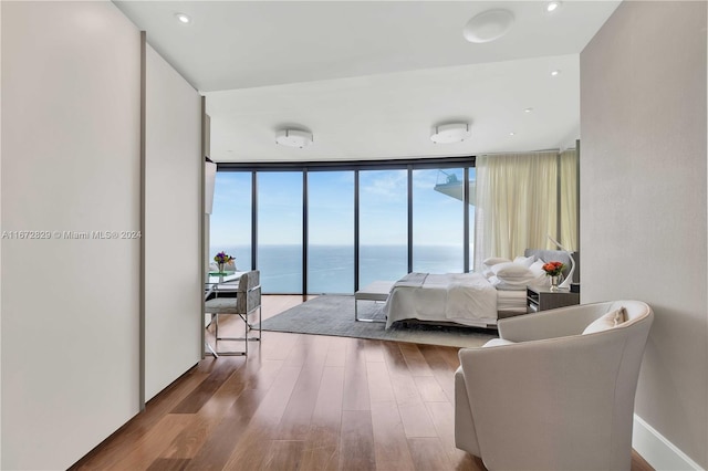 bedroom featuring a water view, a wall of windows, and hardwood / wood-style floors