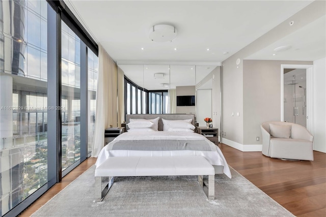 bedroom featuring multiple windows, wood finished floors, and baseboards