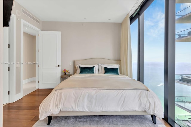 bedroom with a water view, multiple windows, and dark hardwood / wood-style floors