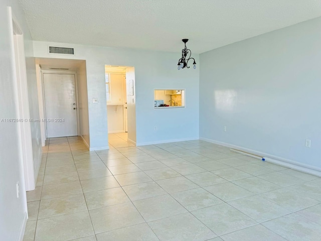 unfurnished room featuring visible vents, baseboards, light tile patterned floors, and a chandelier