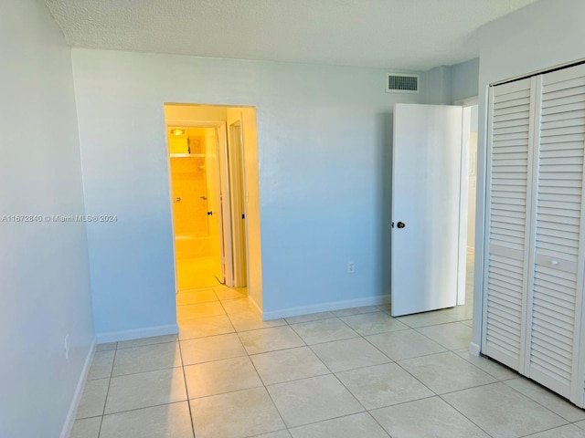 unfurnished bedroom with baseboards, a closet, light tile patterned flooring, and visible vents