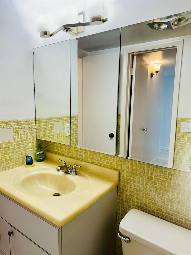 half bathroom with toilet, tile walls, decorative backsplash, and vanity