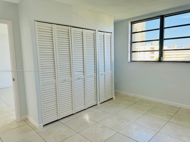 unfurnished bedroom with light tile patterned flooring, baseboards, and a textured ceiling