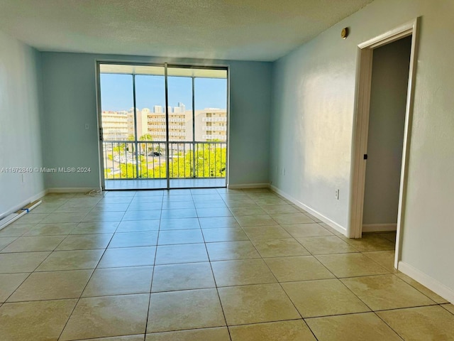 empty room with a textured ceiling and light tile patterned flooring