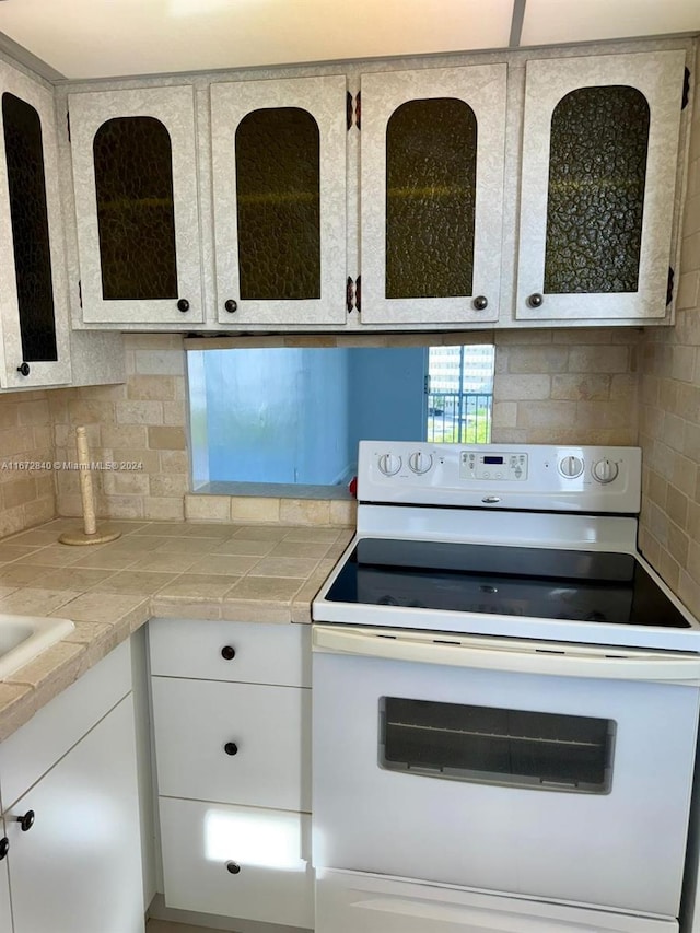 kitchen featuring white cabinets, tile countertops, tasteful backsplash, and electric range