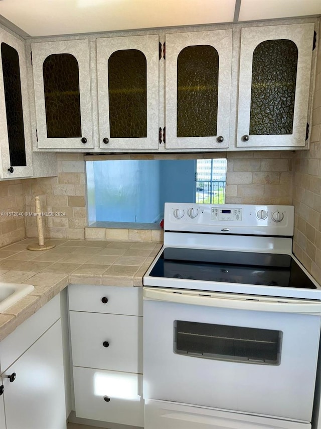 kitchen featuring white cabinetry, tile countertops, tasteful backsplash, and electric stove