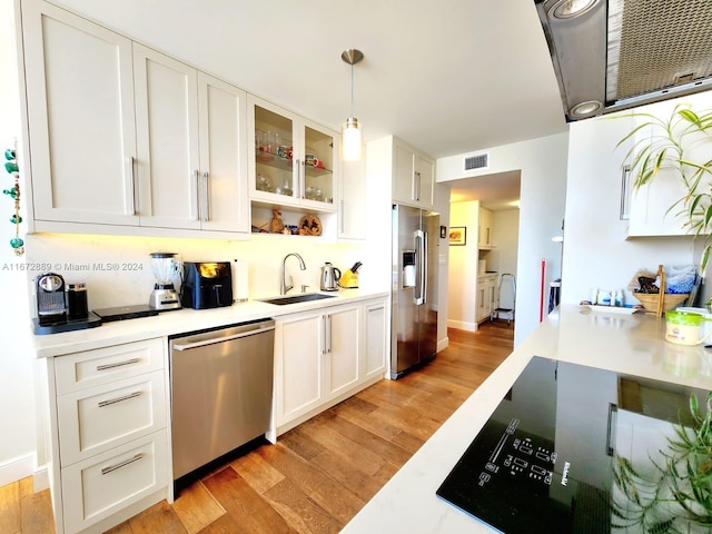 kitchen with light hardwood / wood-style floors, sink, white cabinets, appliances with stainless steel finishes, and decorative light fixtures