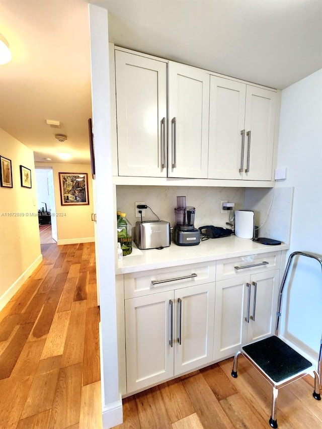 bar with light hardwood / wood-style floors and white cabinets