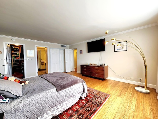 bedroom featuring light hardwood / wood-style flooring, crown molding, and a closet