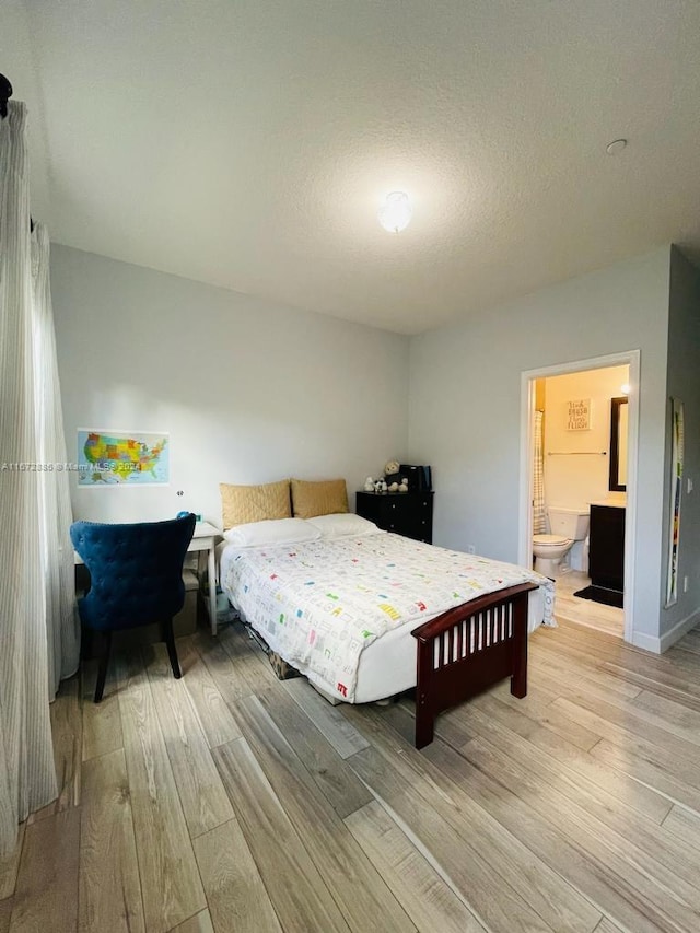 bedroom with a textured ceiling, wood-type flooring, and connected bathroom