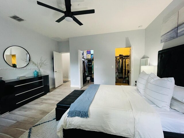 bedroom featuring ceiling fan, a closet, light wood-type flooring, and a spacious closet