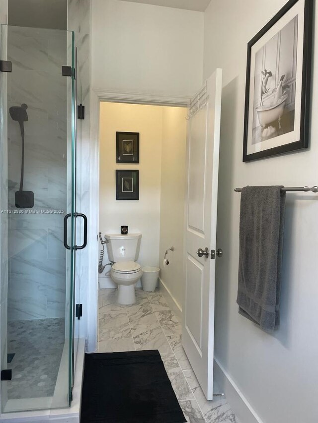 bathroom with a shower with door and toilet