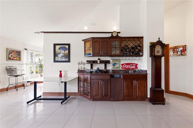 bar with vaulted ceiling, light tile patterned flooring, and stainless steel dishwasher