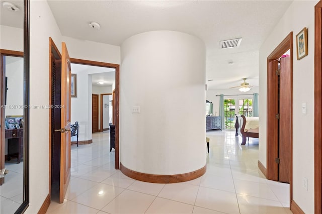 hallway with a textured ceiling and light tile patterned floors