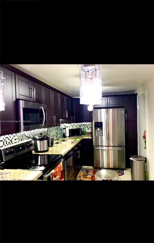 kitchen featuring decorative backsplash, stainless steel appliances, and light stone countertops