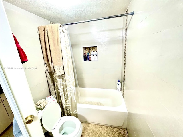 bathroom with a textured ceiling, shower / bath combo with shower curtain, and toilet