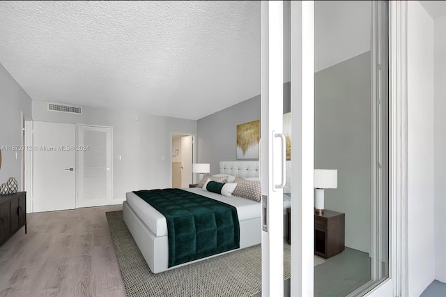 bedroom with a textured ceiling and light wood-type flooring