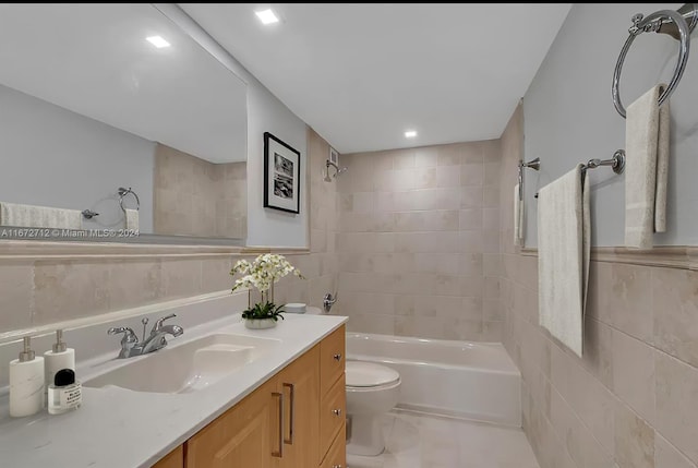 full bathroom featuring vanity, tile walls, tiled shower / bath combo, and toilet