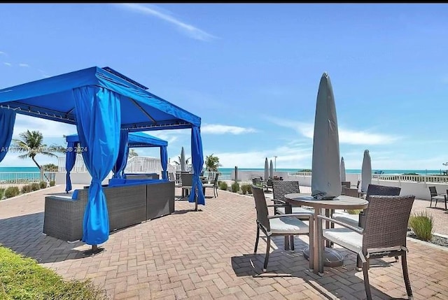 view of patio / terrace featuring a gazebo, a water view, a beach view, and an outdoor hangout area