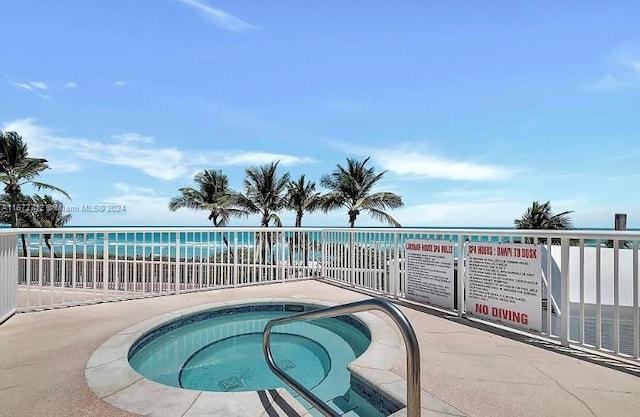 view of pool with a water view, a beach view, and a hot tub