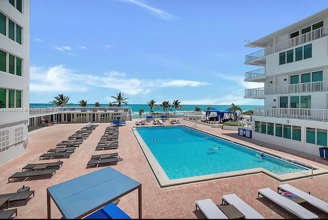 view of swimming pool featuring a water view and a patio area