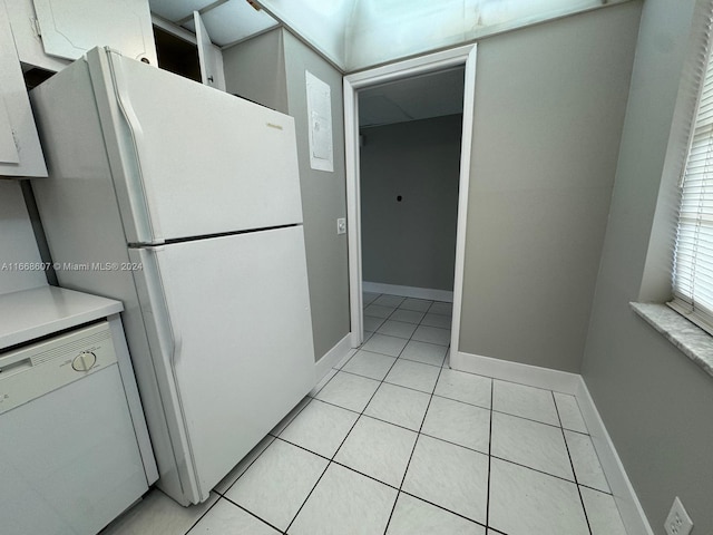 kitchen with white appliances, light tile patterned floors, and white cabinetry